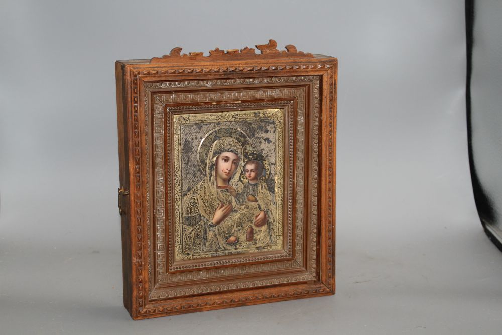 A late 19th century Russian tempera on panel icon, with silver gilt oklad dated 1889, housed in an ornate carved wood casement frame,